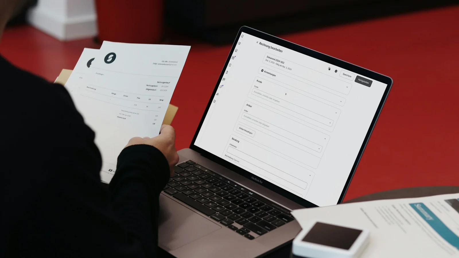 A person sitting at a desk reviewing handwritten notes next to a laptop