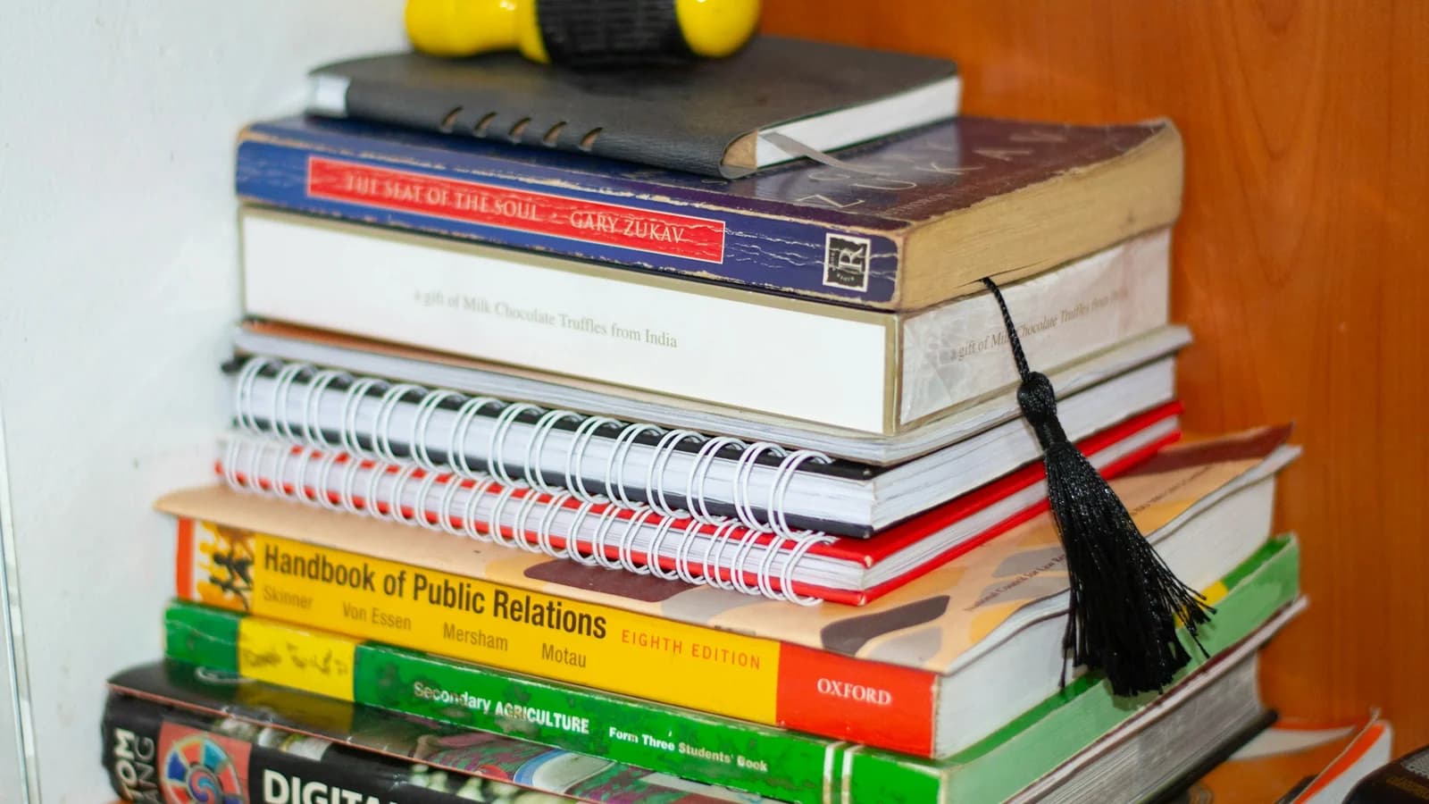 A stack of school textbooks with a yellow object on top