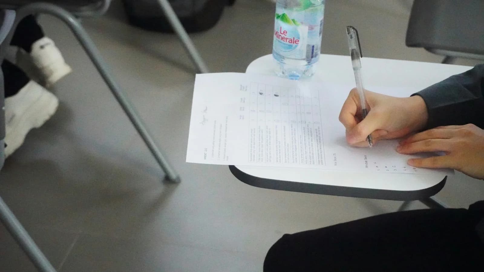 A student writing answers on lined paper during an examination
