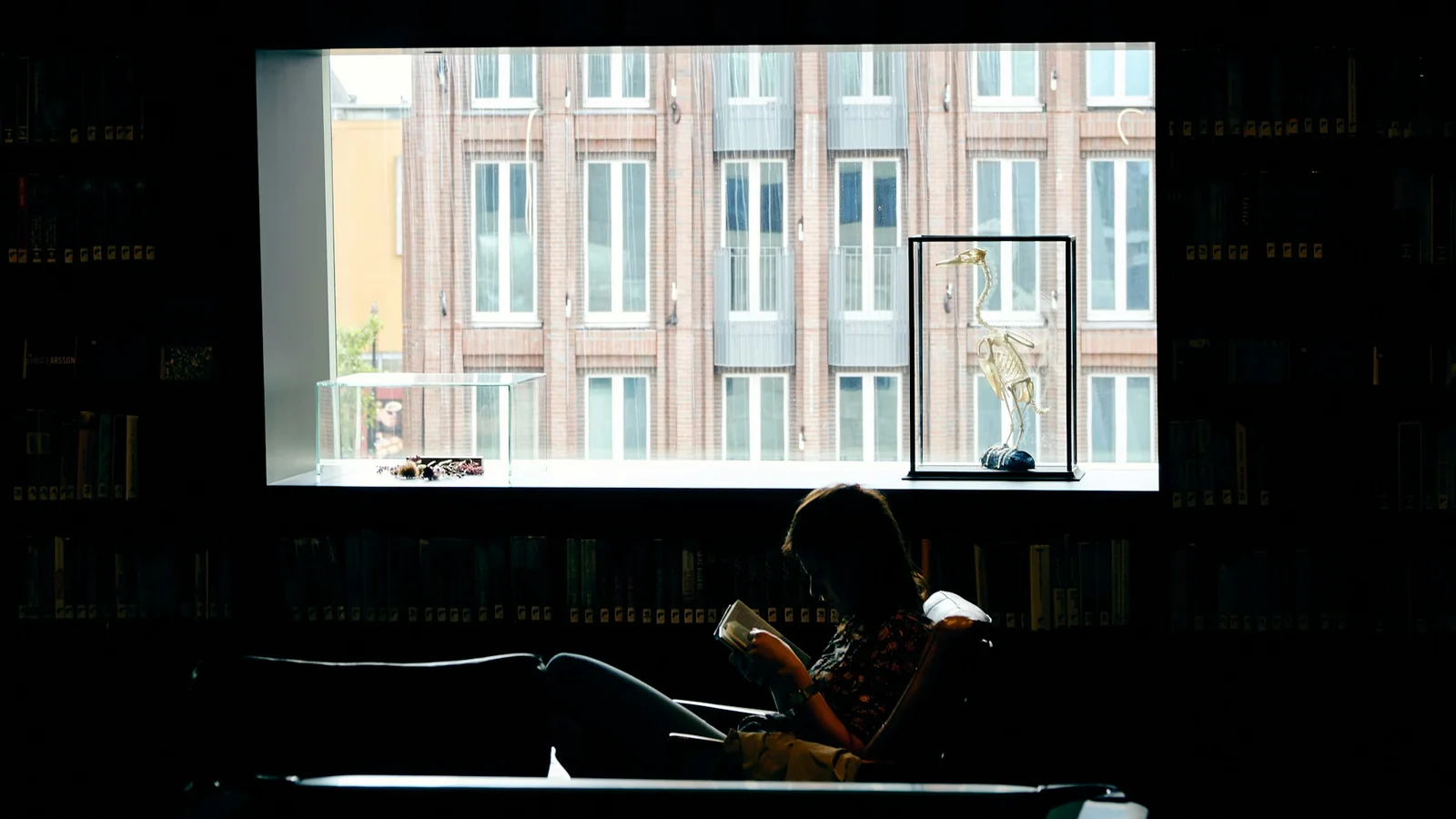 A man in a black jacket sitting on a chair in a quiet space