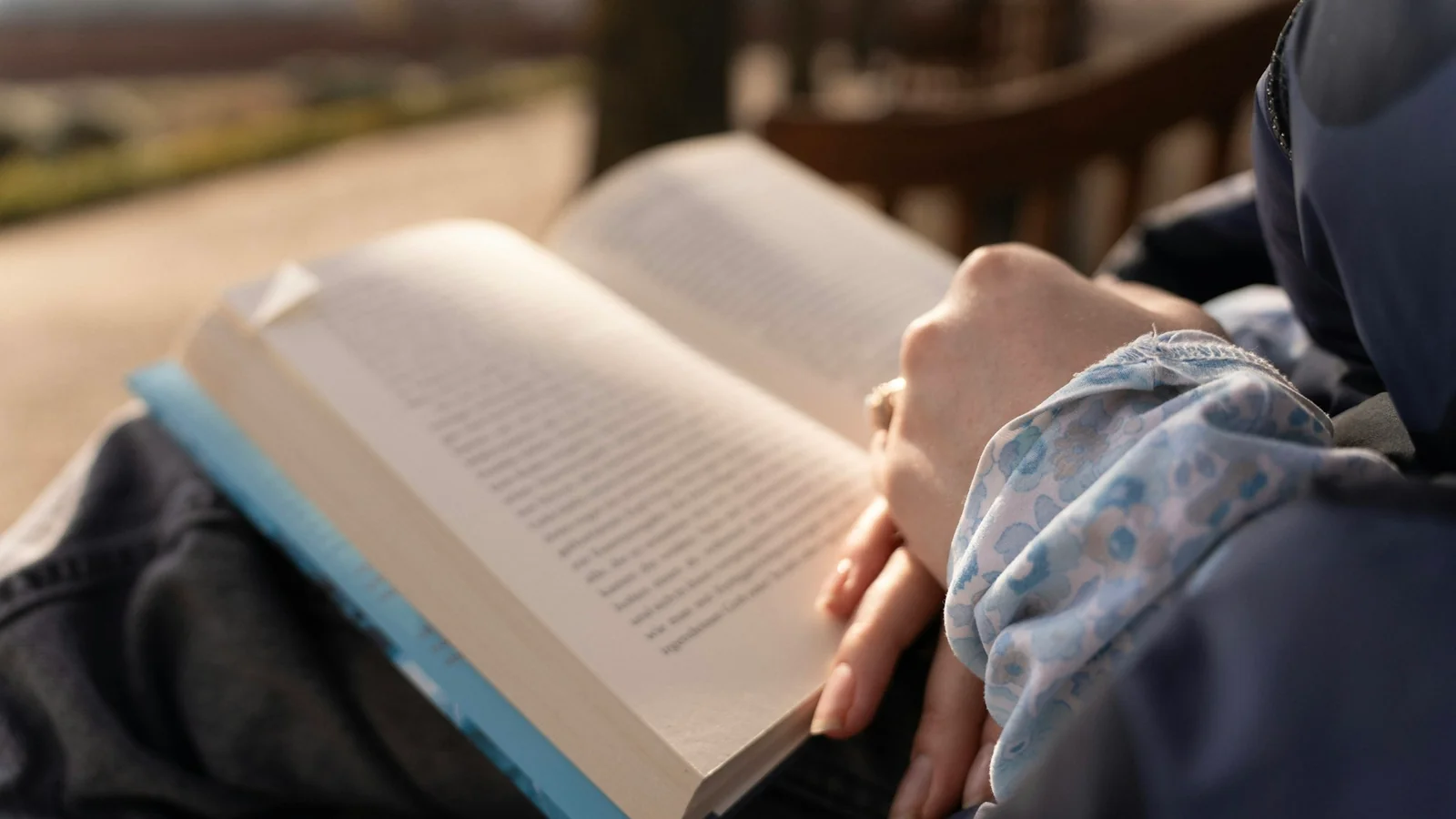 A person reading an open book outdoors