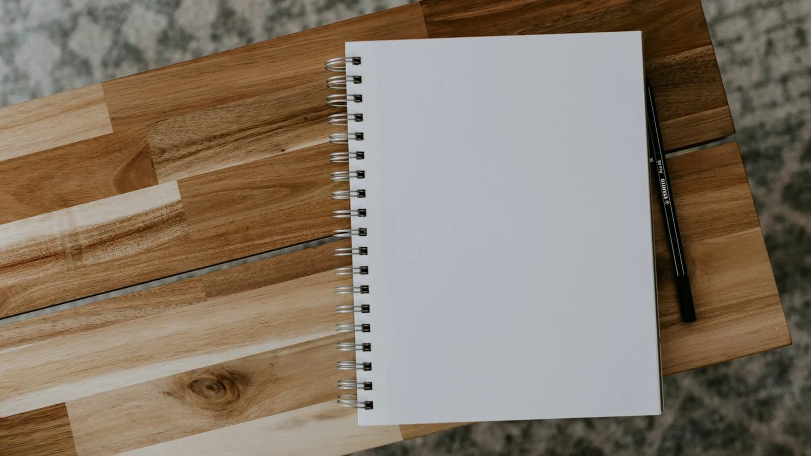 A blank spiral notebook lying open on a wooden table