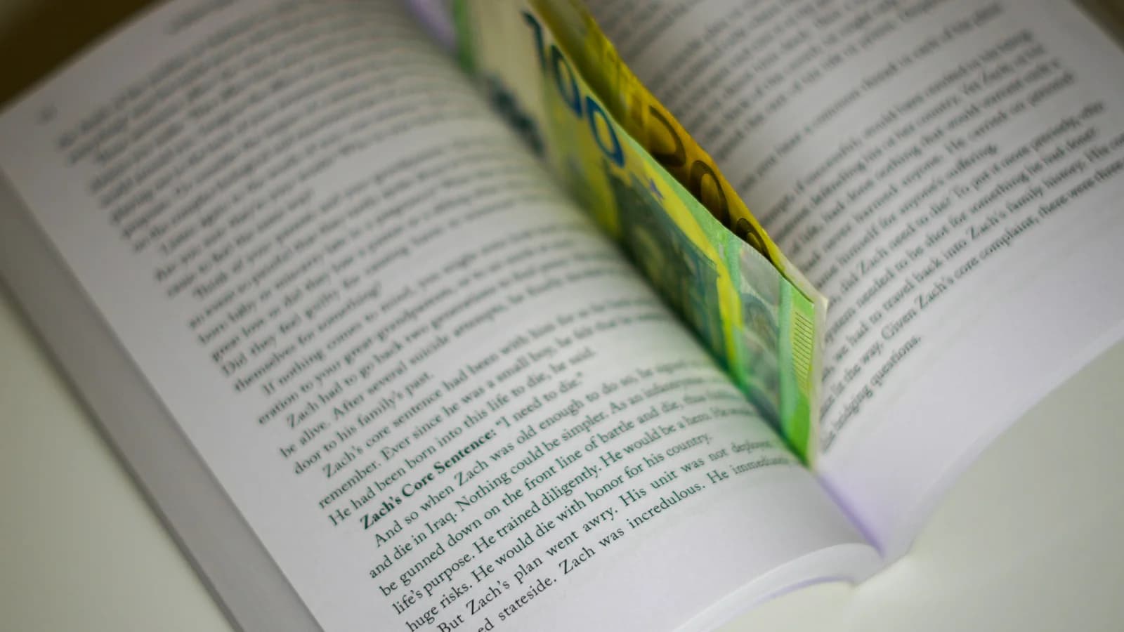 An open book on a table with a folded piece of paper sticking out as a bookmark