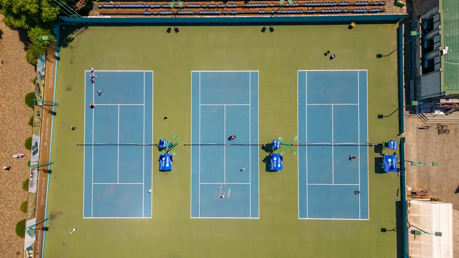 Aerial view of three blue tennis courts arranged side by side