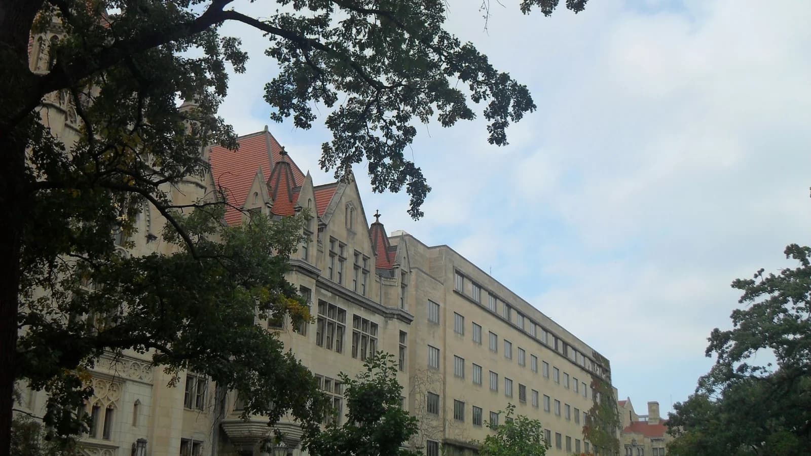 Historic university buildings under a partly cloudy sky