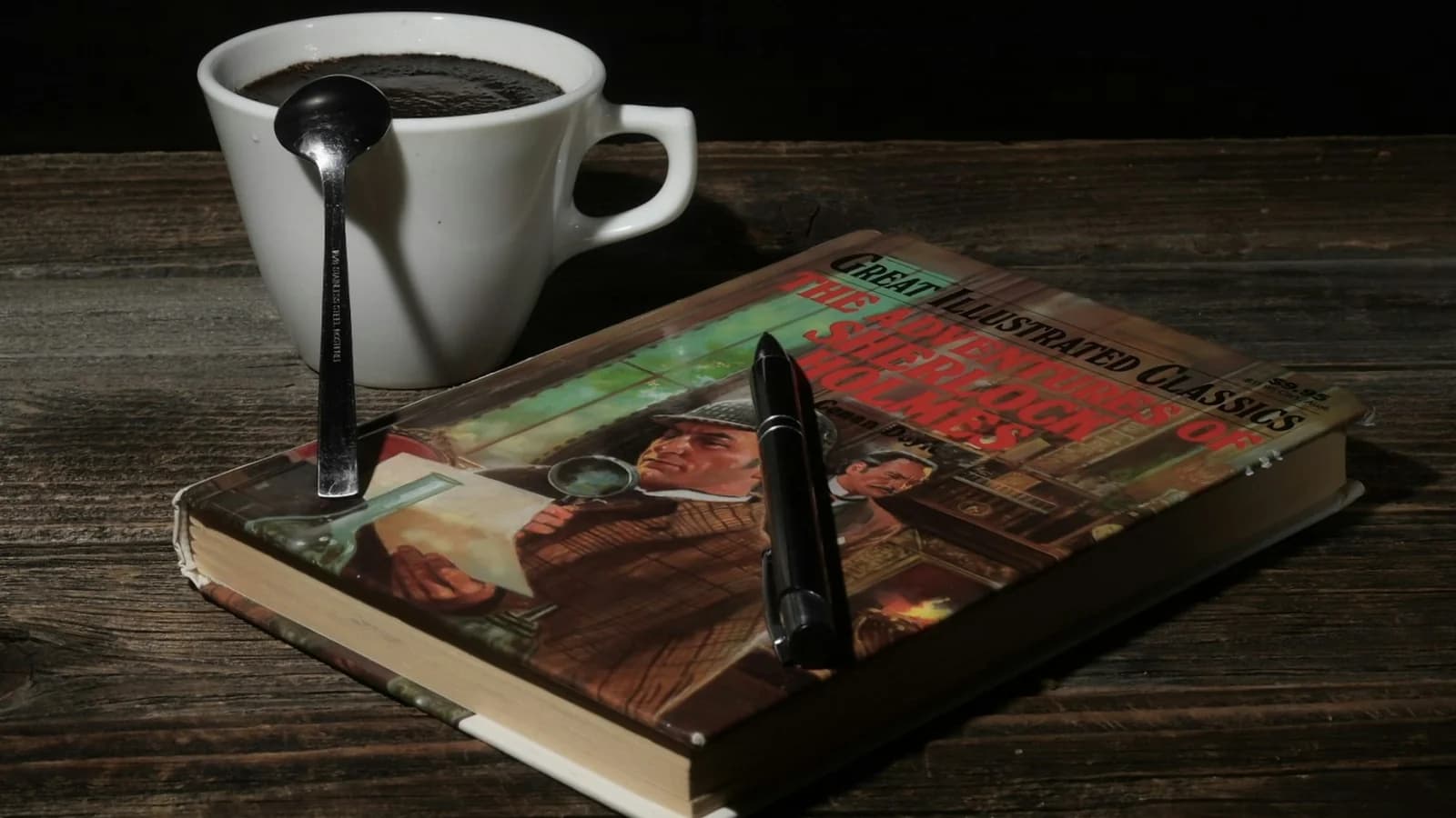 A coffee cup, an open book, and a spoon arranged on a desk