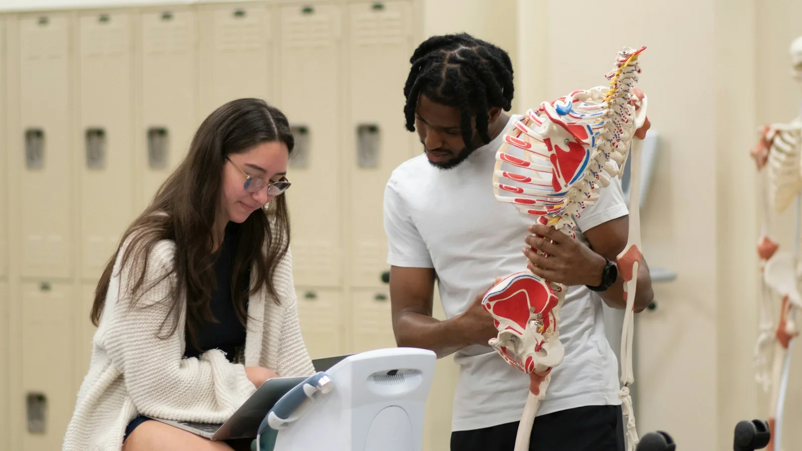 Medical students reviewing a human skeleton model during anatomy preparation