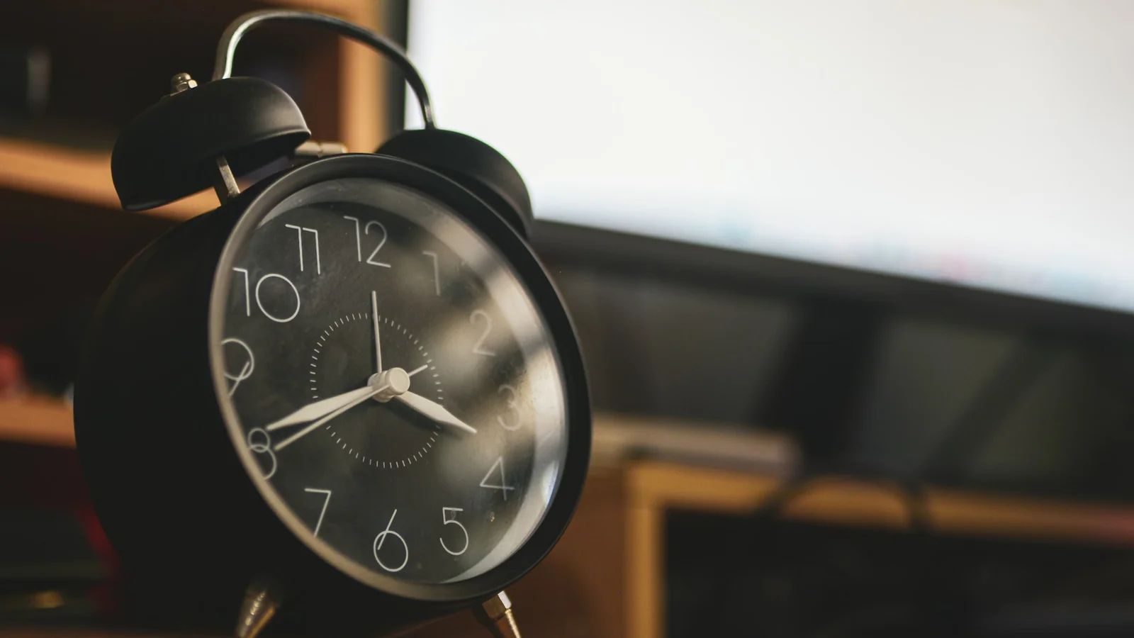 A black alarm clock on a wooden surface
