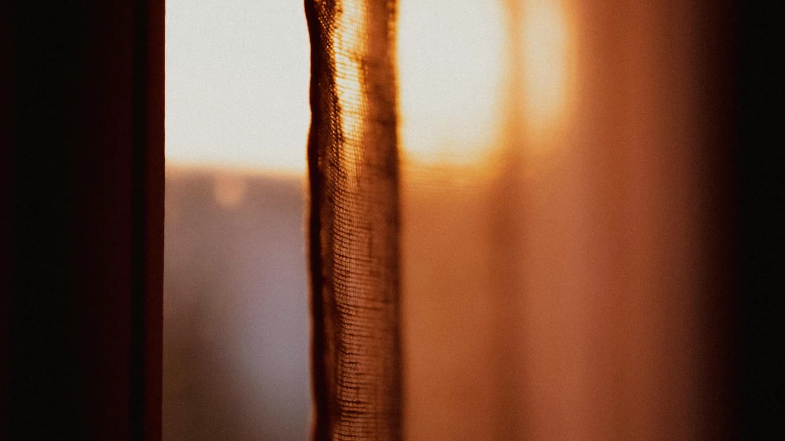 Soft morning light filtering through a curtain at a window