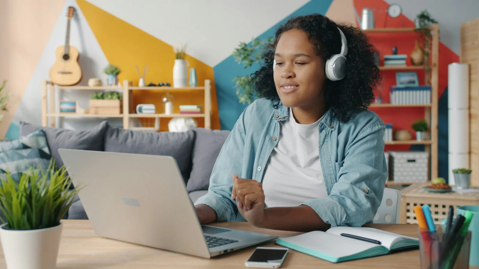 Young woman wearing over-ear headphones while working on a laptop